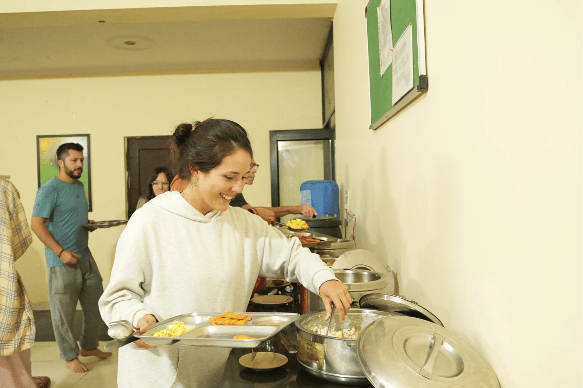 Yoga student serving nutritious vegetarian meals at Aatm Yogashala dining hall in Rishikesh