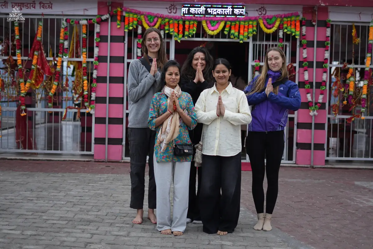 International yoga students posing with namaste prayer gesture at Maa Bhadrakali Temple excursion during 300 Hour Yoga TTC Rishikesh