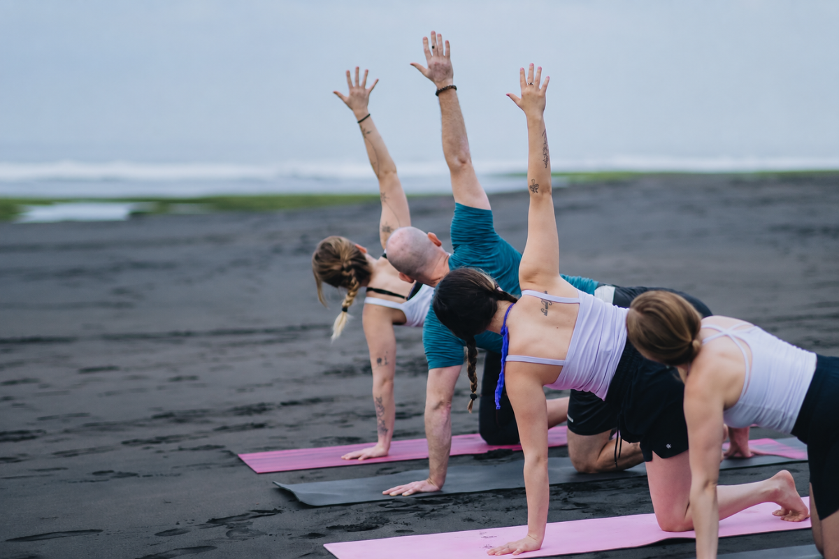 Yoga practice on black sand beach during the 100 Hour Yoga Teacher Training in Bali